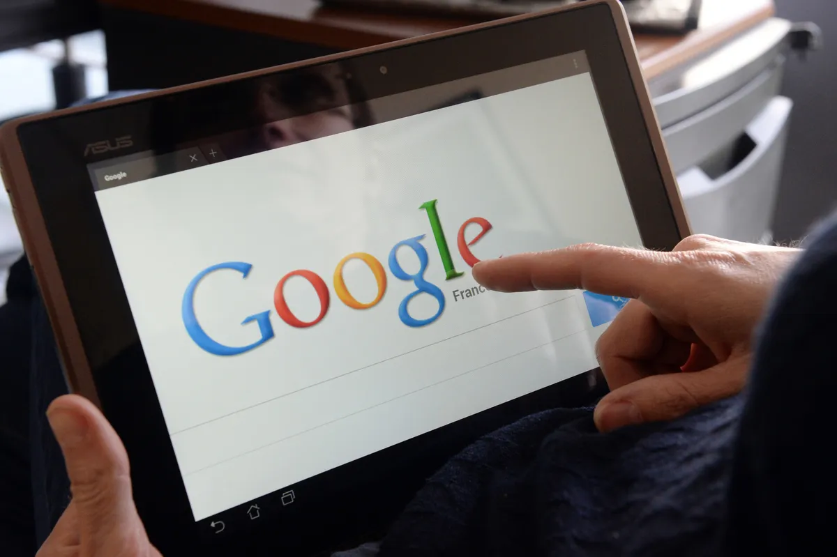 woman choosing Google Search (or Google Web Search) web search engine front page on her tablet.