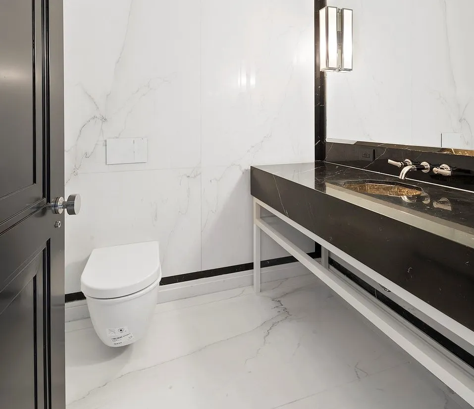 A larger copper sink stretches across the  powder room, otherwise bare if not for the tankless floating toilet.