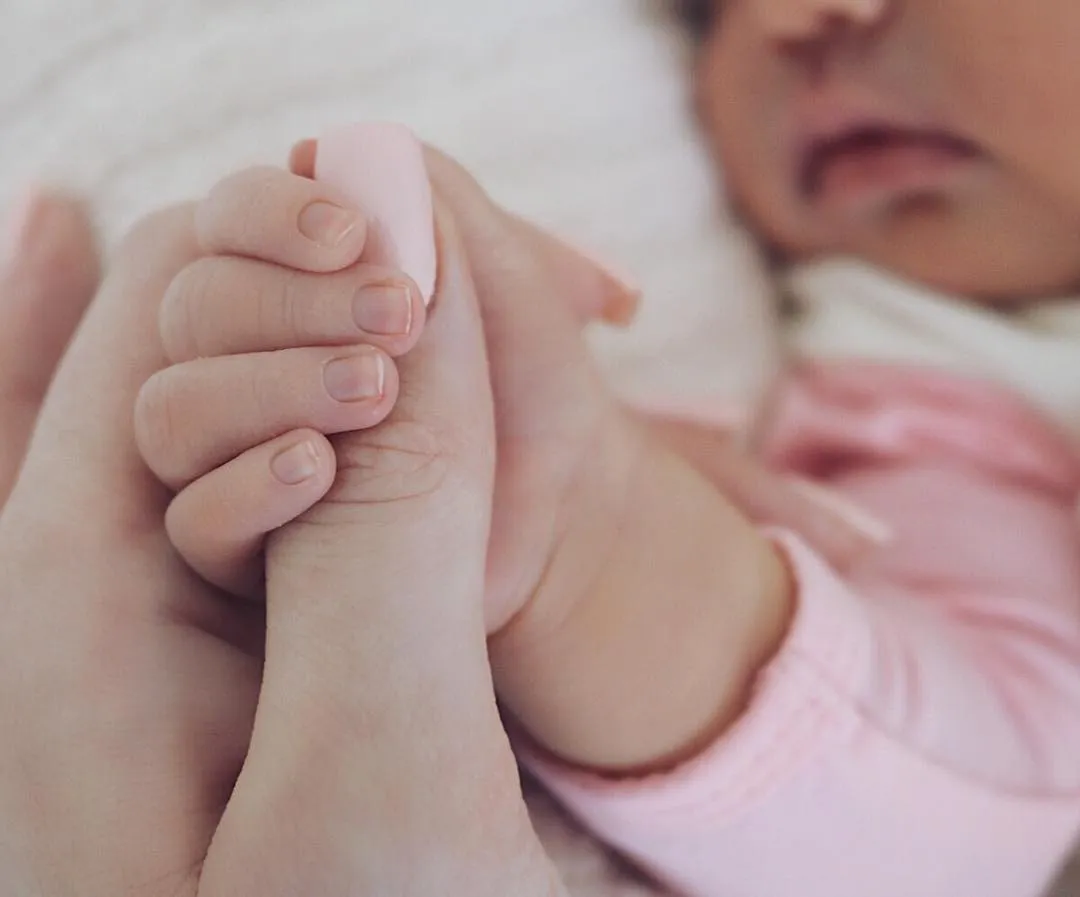 stormi holding her moms thumb 