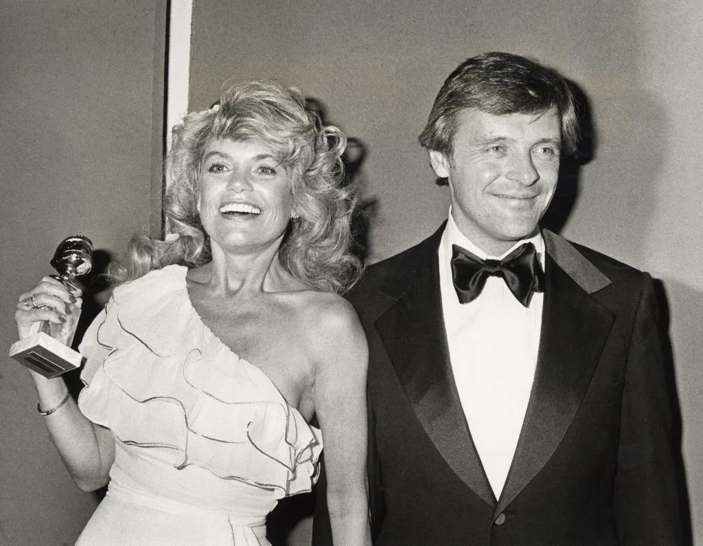 Anthony Hopkins stands next to a woman who holds a Golden Globe.